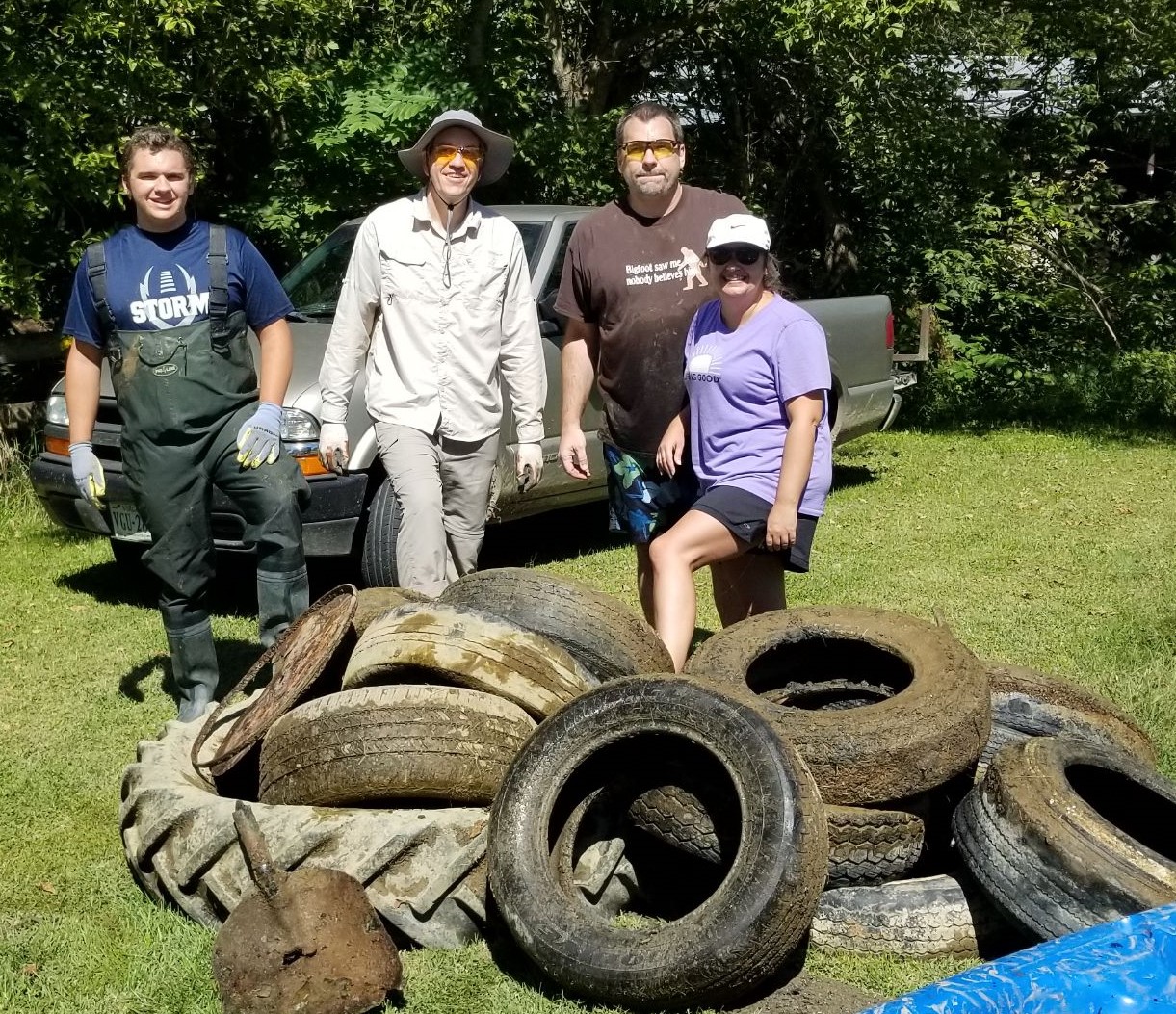 4 people stand  in front of old tires