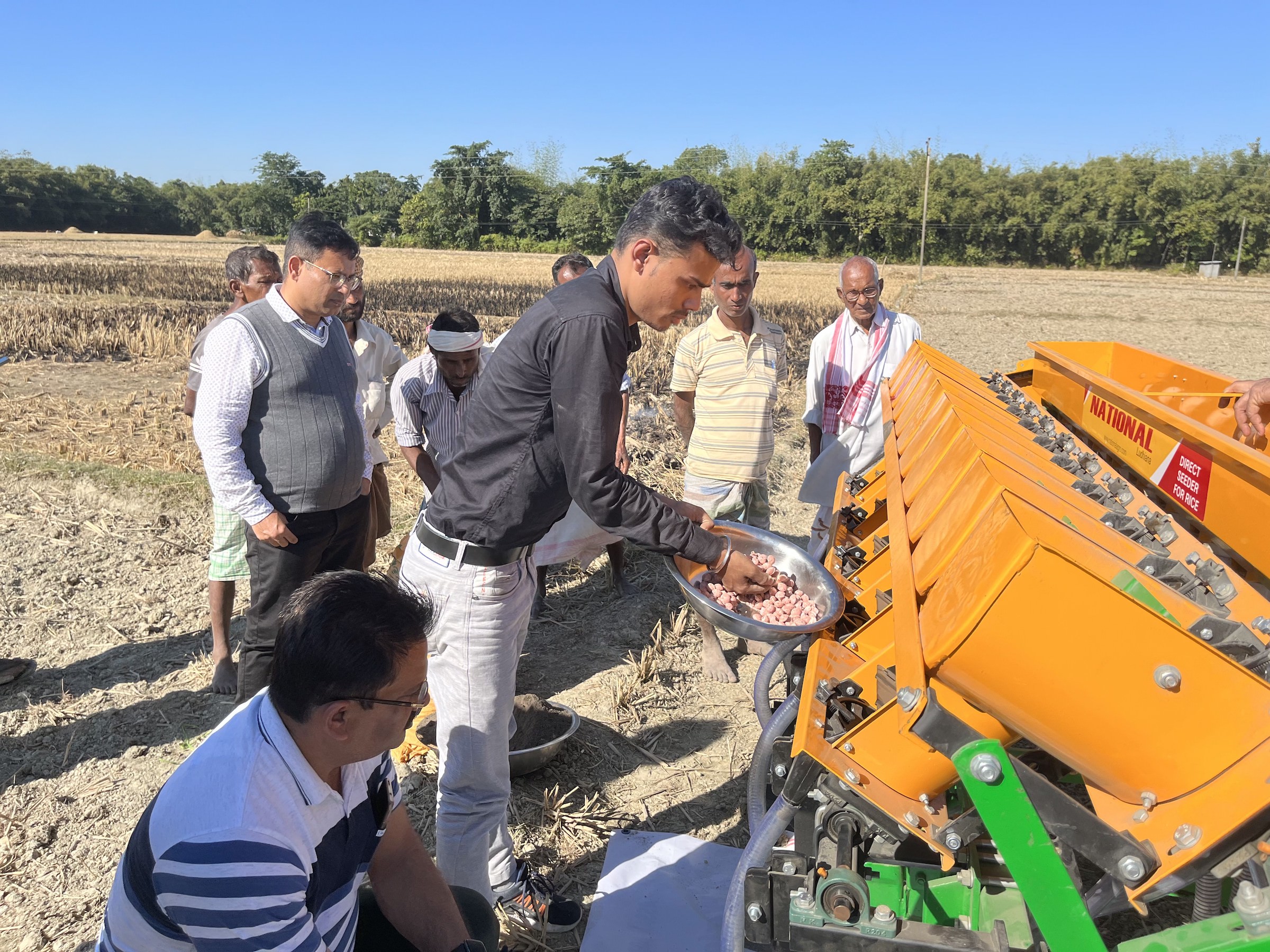 Men load fertilizer briquettes into a seed and fertilizer drill