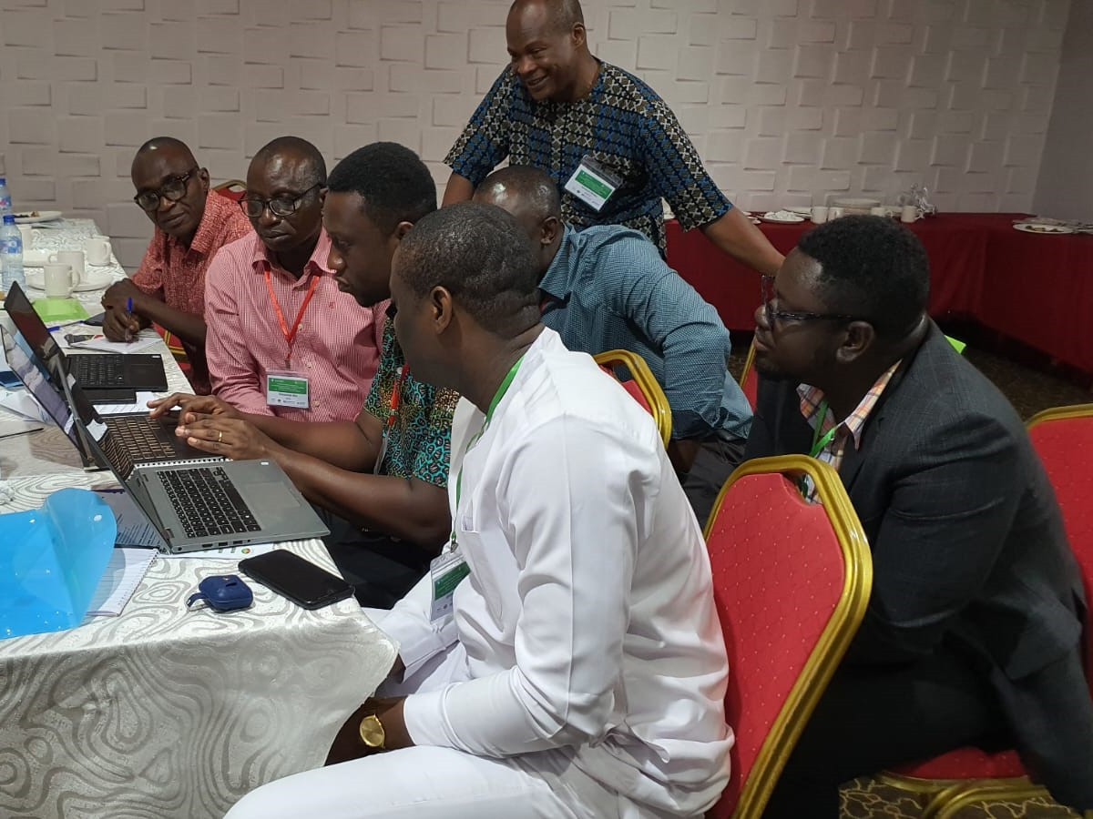 Men sit around a computer at a validation workshop