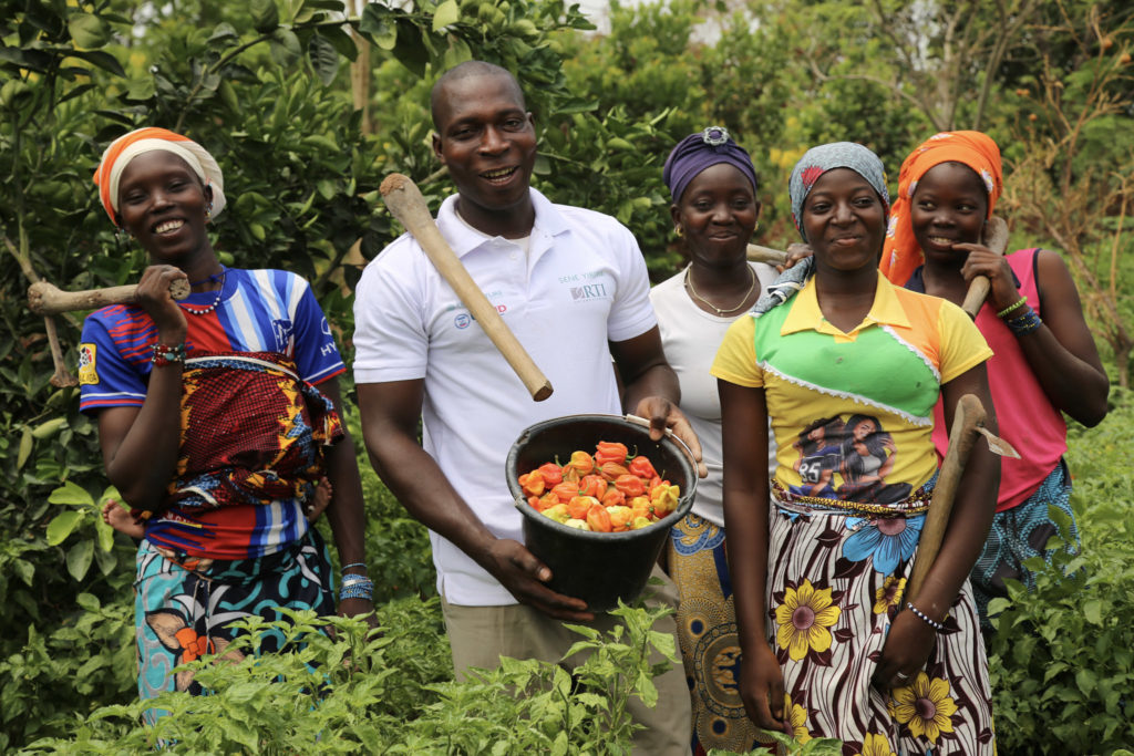 A Malian family smiles while picking peppers