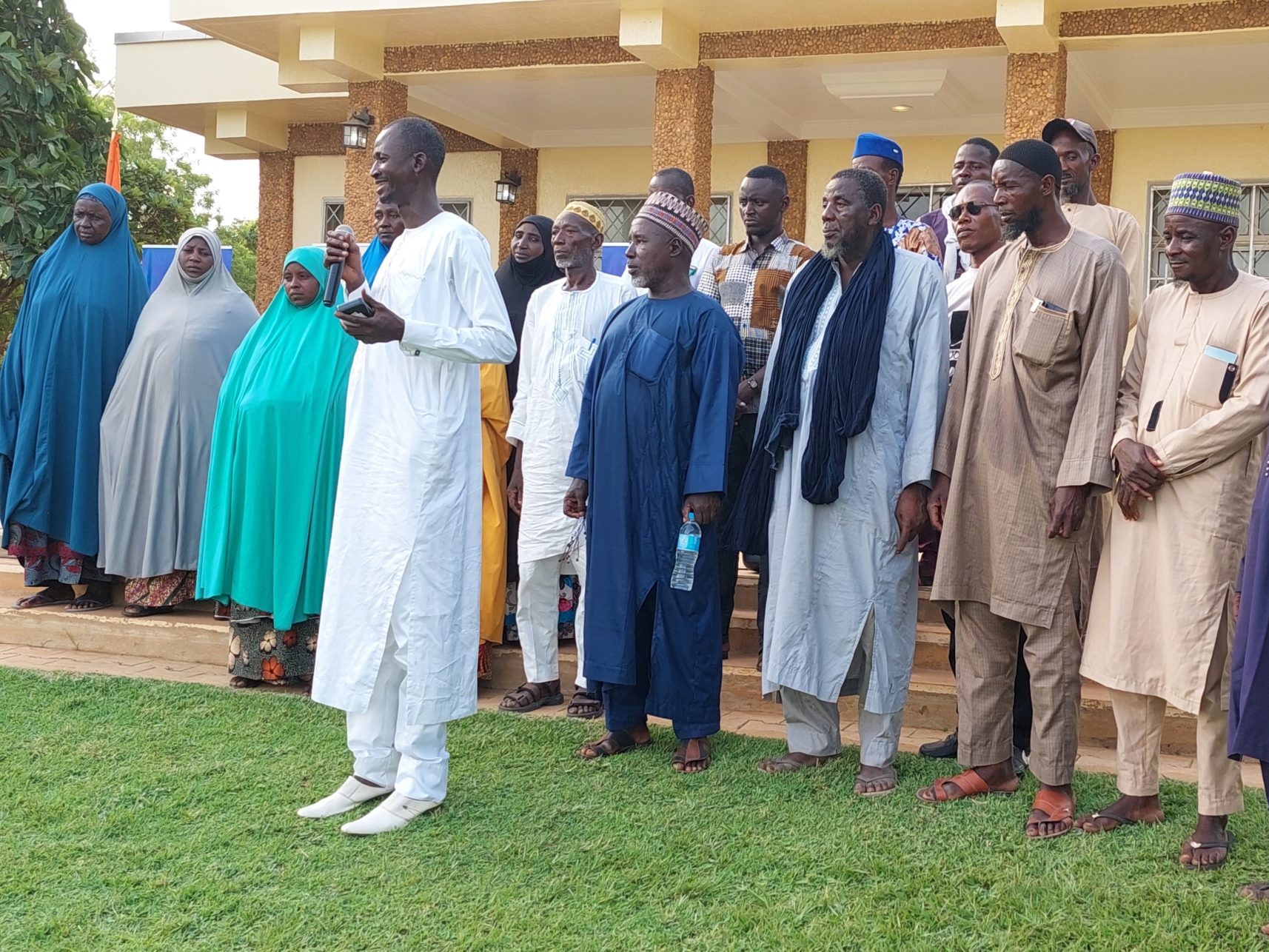 Stakeholders stand behind a host with a microphone