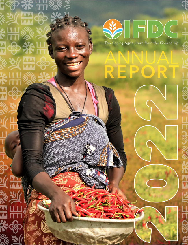 A woman smiling holding a basket of peppers with her child.