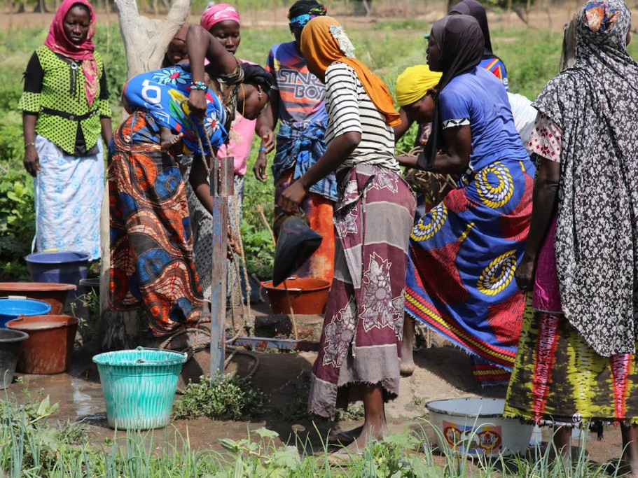 A group of women stand at an irrigation pump