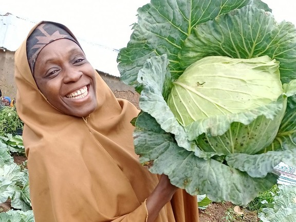 Saudatu Yakubu, a 29-year-old female smallholder farmer from Nigeria, holds up a cabbage
