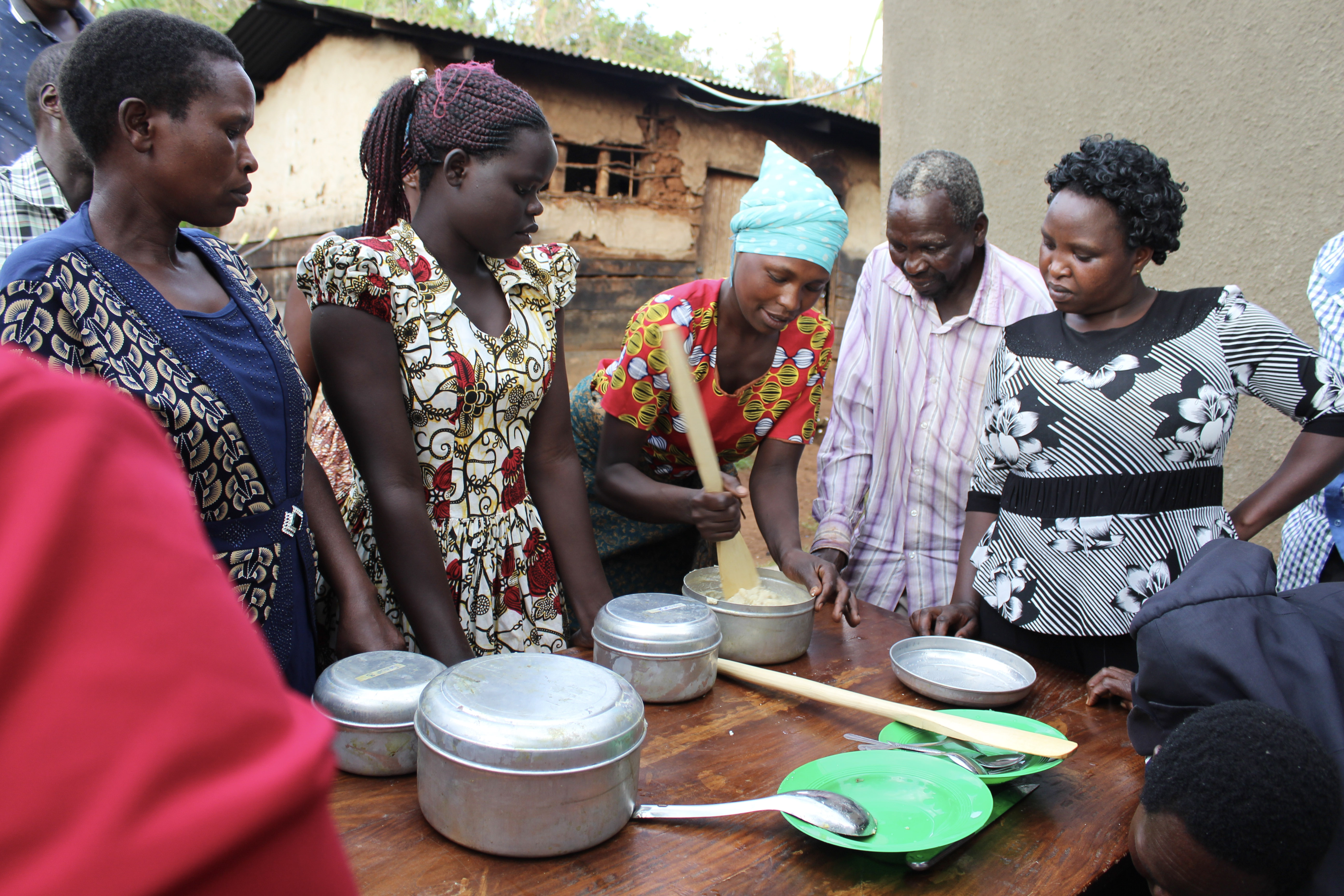 Community members in Uganda watch a cooking demonstration.