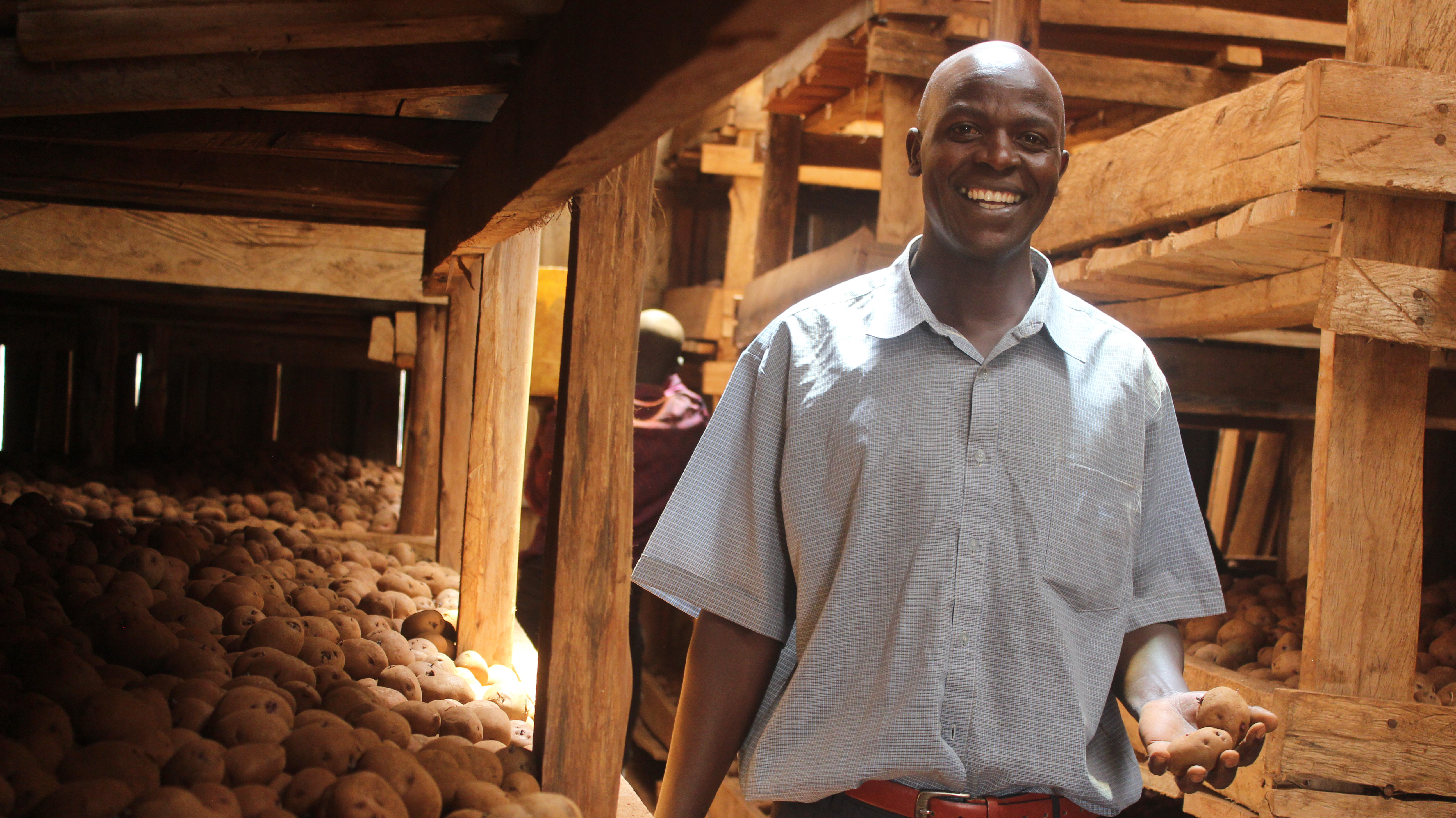 Bosei Michael- chairperson of the MIFA production committee showing the season's seed for sale in the group's Diffuse Light Store located in Kween district.