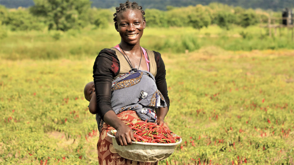 Young mother in Benin holds a bowl of peppers