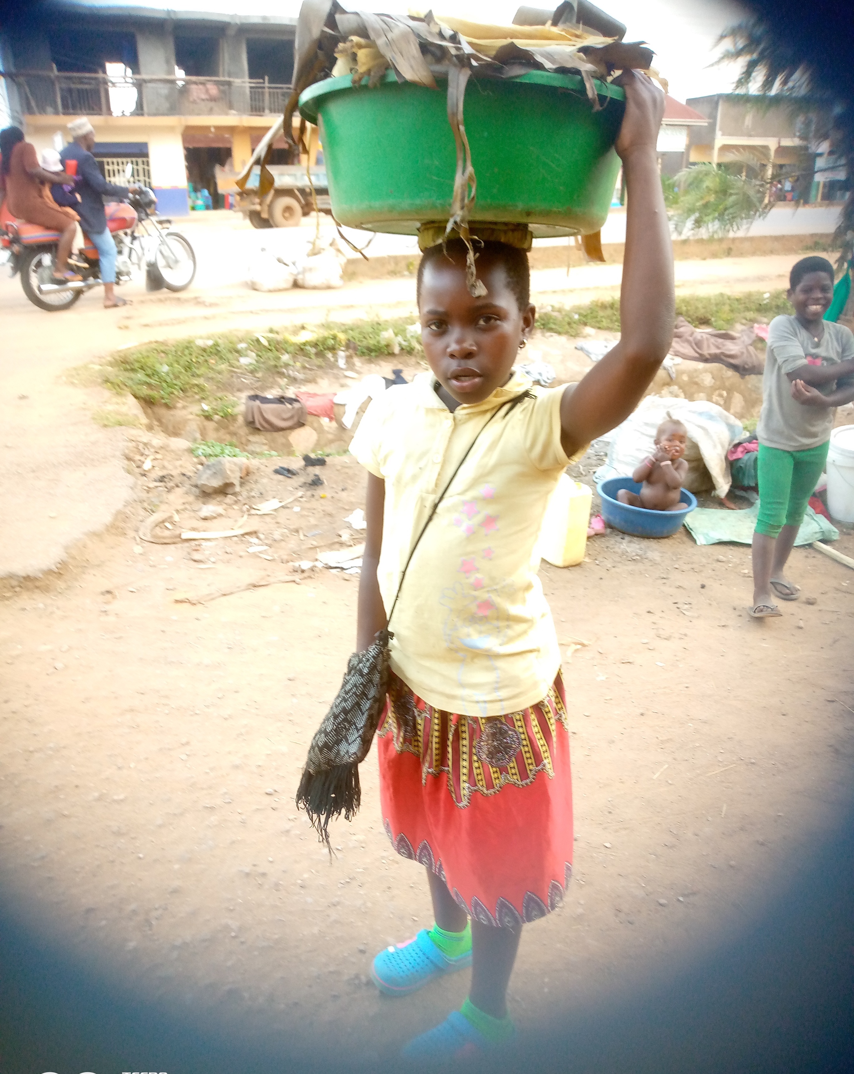 small girl with tub of maize on her head