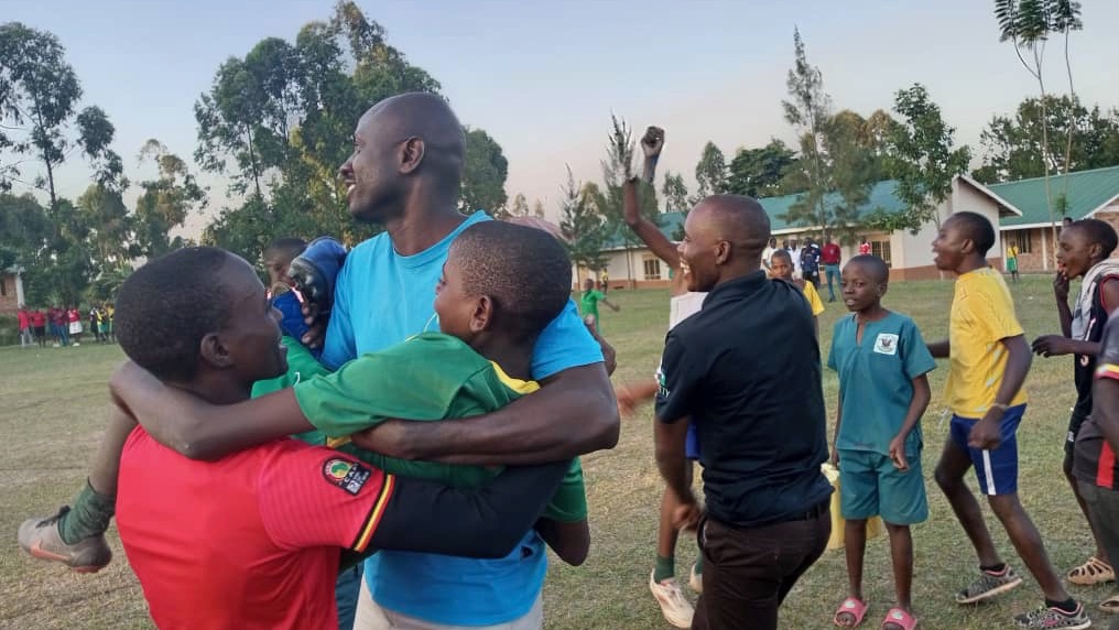 Headteacher John Robert carrying the scorer while others cheer!