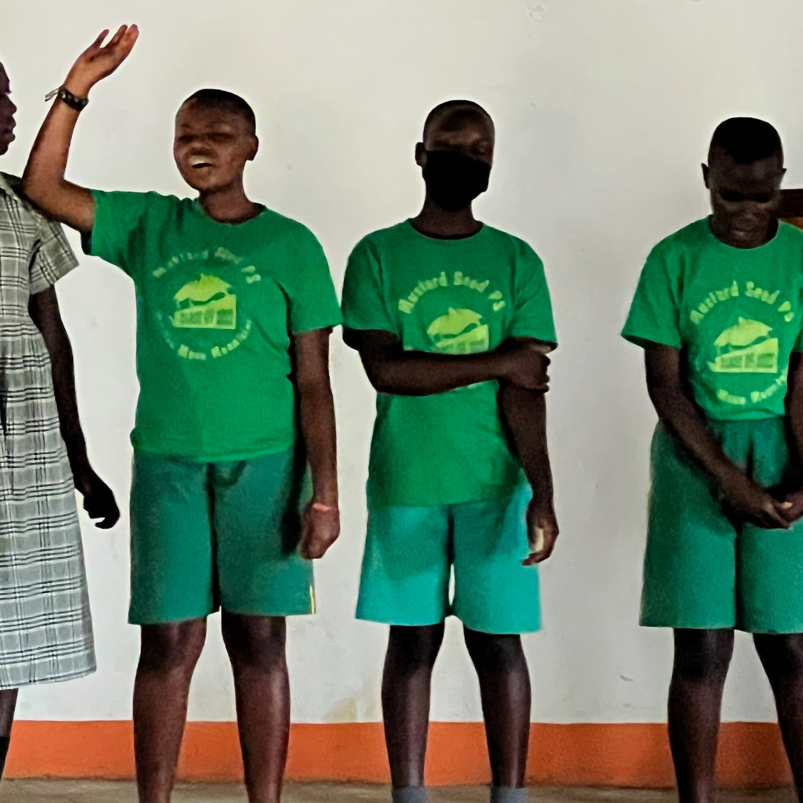 Girls singing and dancing in school uniforms- green shorts and shirts.